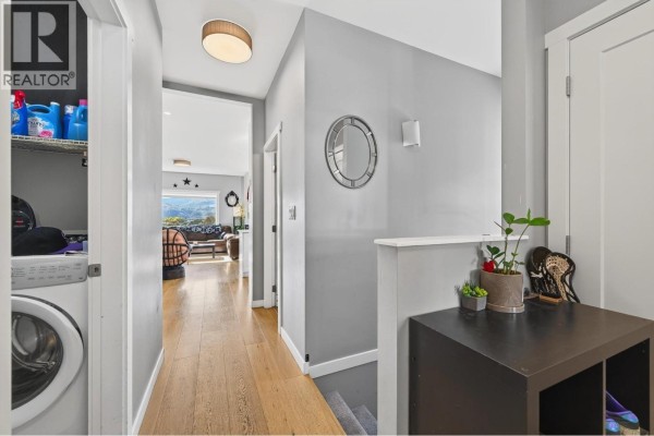 Interior hallway with laundry machines, grey walls, and light wood flooring. - 1900 Ord Road Unit# 21, Kamloops