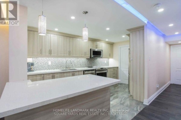 Modern kitchen with light wood cabinets, quartz countertops, and stainless steel appliances. - 1901 - 10 Tangreen Court, Toronto