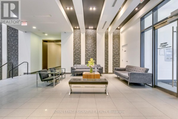 A contemporary apartment building lobby with grey tile floors and modern seating. - 1901 - 20 Bruyeres Mews, Toronto