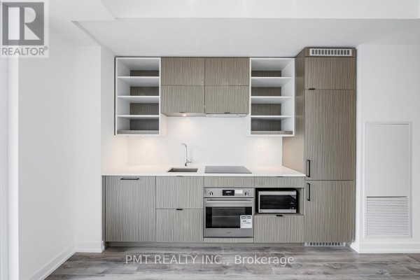 Close-up of a modern kitchen with light wood cabinets and integrated appliances. - 1901 - 20 Edward Street, Toronto