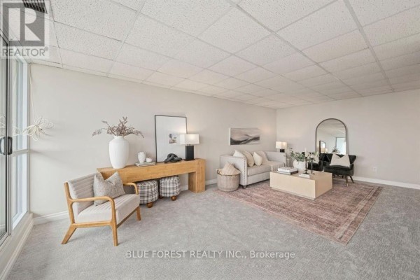 Living room with light gray carpet, beige sofa, and accent chairs. - 1901 - 389 Dundas Street, London East