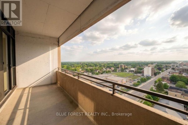 Balcony overlooking a suburban landscape with trees and buildings. - 1901 - 389 Dundas Street, London East