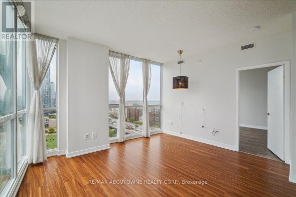 Dining room with a wooden table, chairs, sideboard, and floor-to-ceiling windows. - 1901 - 75 Queens Wharf Road, Toronto