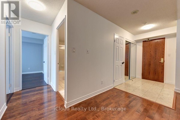 Interior hallway with hardwood floors and doorways to rooms. - 1902 - 156 Enfield Place, Mississauga