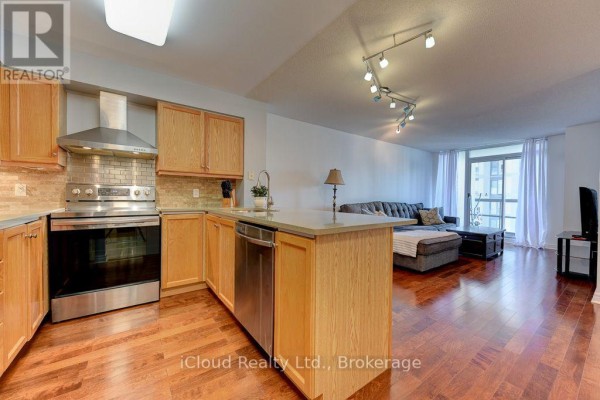 Kitchen and living area with island, sofa, and balcony view. - 1902 - 156 Enfield Place, Mississauga