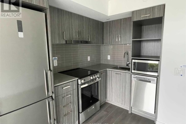 Close-up of a modern apartment kitchen with grey striped cabinets and stainless steel appliances. - 1902 - 219 Dundas Street E, Toronto
