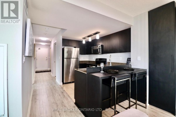 Modern kitchen with dark cabinets, stainless steel appliances, and a granite countertop island. - 1902 - 381 Front Street, Toronto