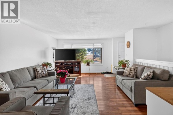 A spacious living room with multiple seating areas, a large TV, and a view of the outdoors. - 1904 22nd Street, Vernon