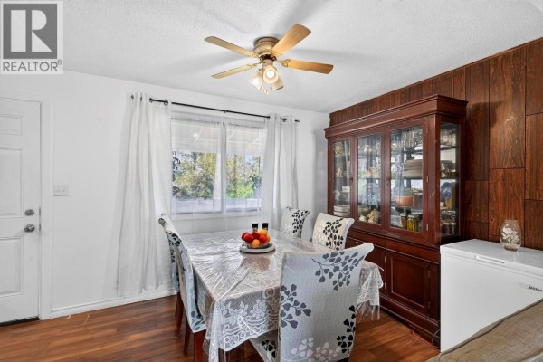 A dining area with a table, chairs, and a large wooden display cabinet with glass doors. - 1904 22nd Street, Vernon