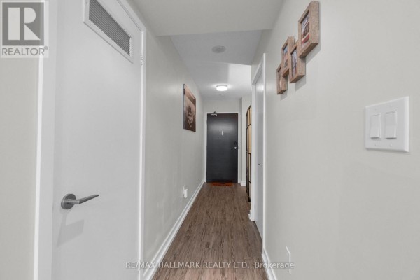 Interior hallway with white walls, dark wood-look flooring, and several doors. - 1905 - 151 Dan Leckie Way, Toronto