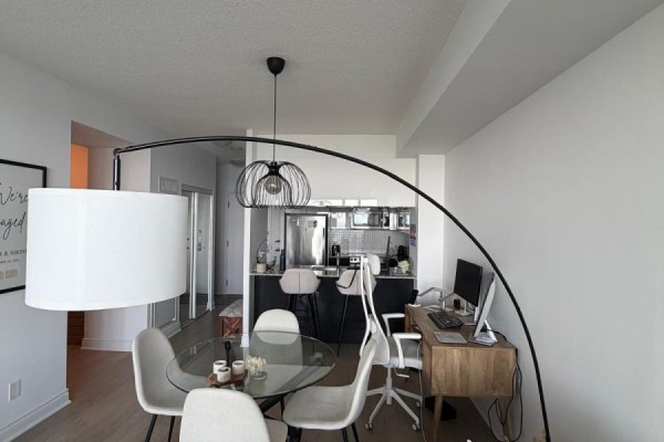 Dining area with a glass table and chairs, adjacent to a kitchen and workspace. - 1905 - 80 Marine Parade Drive, Toronto