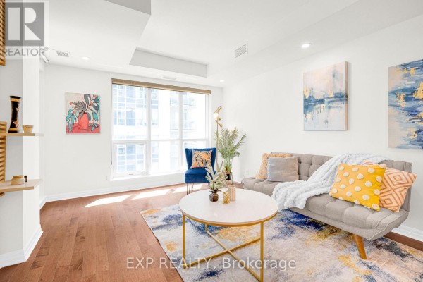 Living room with grey sofa, colorful rug, coffee table, and large window. - 1906 - 242 Rideau Street, Ottawa