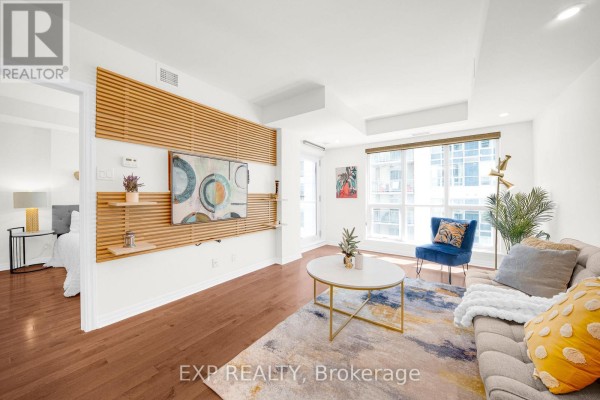 Living room showing sofa, TV wall unit with wooden slats, and partial view of bedroom. - 1906 - 242 Rideau Street, Ottawa