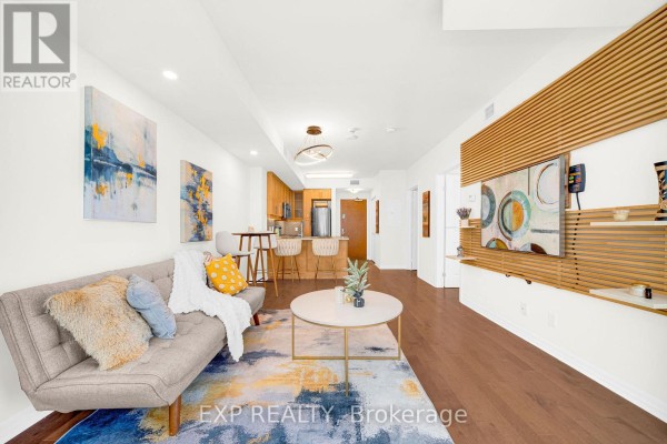 Open concept living area with sofa, TV unit, and kitchen with island seating. - 1906 - 242 Rideau Street, Ottawa