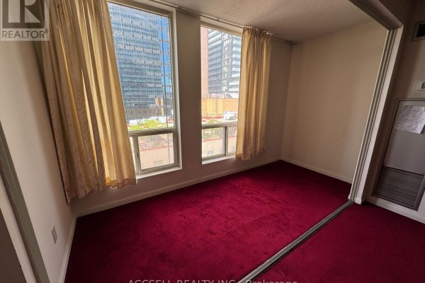 Bedroom with red carpet, two windows with beige curtains, and city view. - 1906 - 25 Grenville Street, Toronto