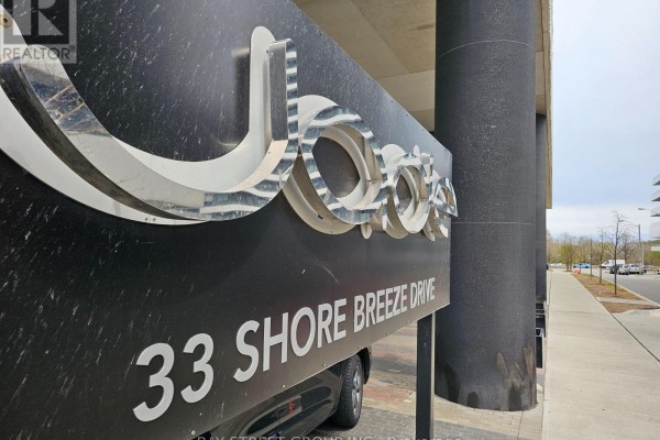 Close-up of the building's metal sign displaying "33 Shore Breeze Drive" and its logo. - 1906 - 33 Shore Breeze Drive, Toronto