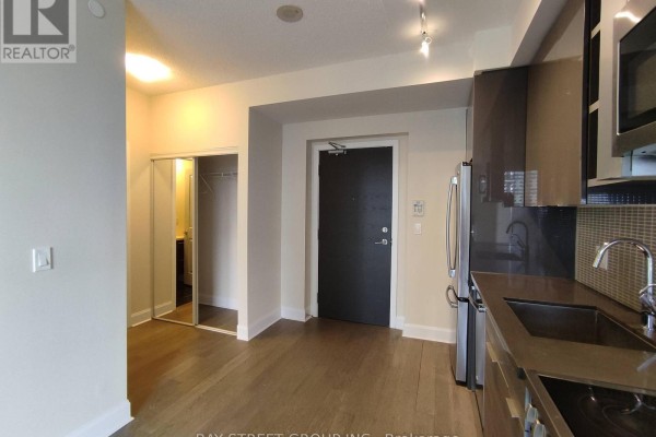 Interior view of an apartment showing a hallway with a closet, a closed door, and a glimpse of a bathroom. - 1906 - 33 Shore Breeze Drive, Toronto