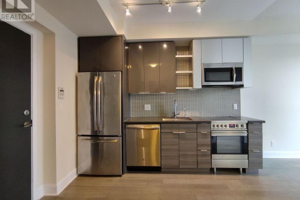 Modern kitchen with stainless steel appliances, dark and white cabinetry, and a light wood floor. - 1906 - 33 Shore Breeze Drive, Toronto