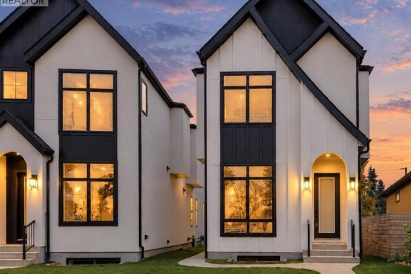Exterior of two modern townhouses with white siding and black trim during sunset. - 1906 5 Street Ne, Calgary