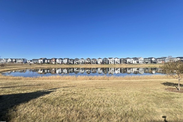 View of houses lining a pond on a clear day with reflections in the water. - 19066 20a Av Nw, Edmonton