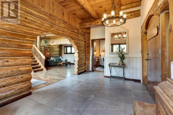 Side view of the log house with stone foundation and attached sunroom. - 19067 Highway 7, Tay Valley