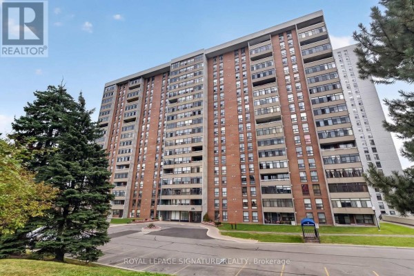 Front view of a tall brick apartment building with trees and grass. - 1908 - 25 Kensington Road, Brampton