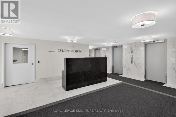 Building lobby with marble floors, a black reception desk, and elevator doors. - 1908 - 25 Kensington Road, Brampton
