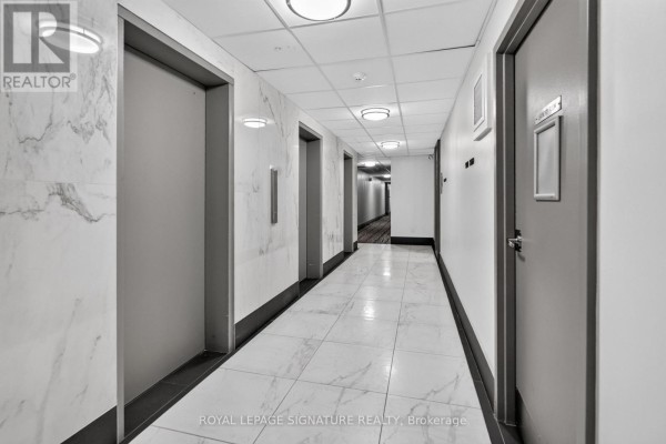 Hallway with marble walls, multiple elevators, and modern lighting fixtures. - 1908 - 25 Kensington Road, Brampton