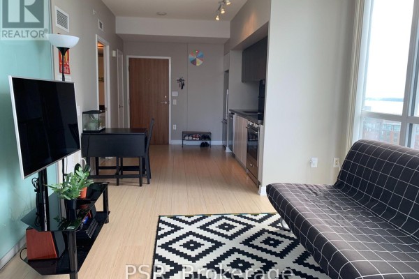 Open-concept living space with sofa, TV, dining table, and kitchen view. - 1908 - 75 Queens Wharf Road, Toronto