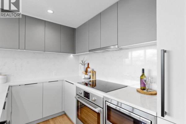 Kitchen with white quartz countertops, grey flat-panel cabinets, induction cooktop, and stainless steel oven. - 1909 567 Emerson Street, Coquitlam