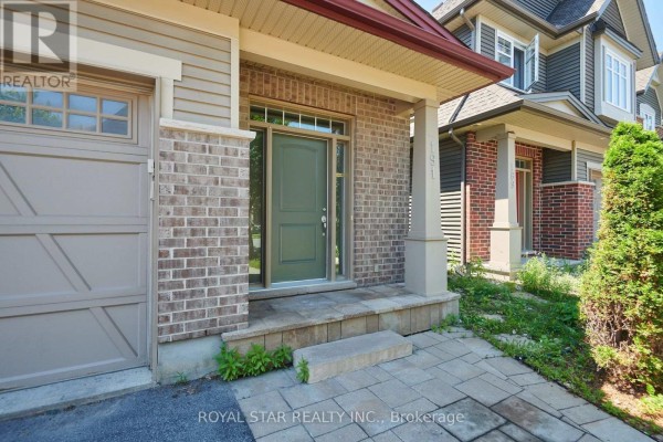 Close-up of the front entrance with a green door, flanked by brickwork and a covered porch with pillars. - 191 Flat Sedge Crescent, Ottawa