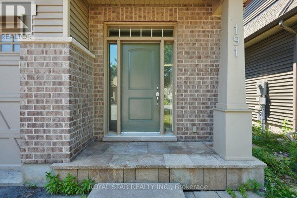 Front door detail showing a beige-green door with glass sidelights and a tiled stoop at the entrance. - 191 Flat Sedge Crescent, Ottawa