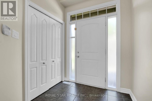 Interior entryway with a white front door, frosted glass panels, dark tiled floor, and two white bi-fold closet doors. - 191 Flat Sedge Crescent, Ottawa