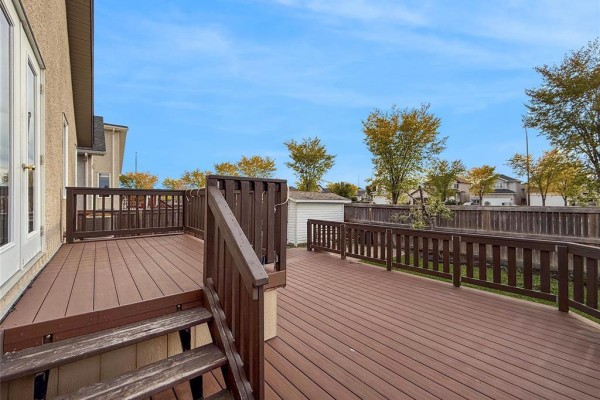 Deck view showing stairs, railing, and a white storage shed in the backyard. - 191 Kingfisher Crescent, Winnipeg
