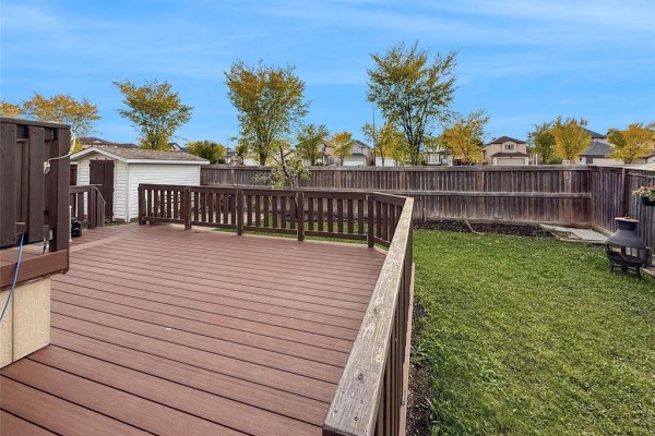 Wooden deck and fenced backyard with a storage shed and mature trees. - 191 Kingfisher Crescent, Winnipeg