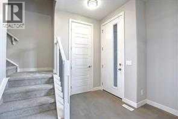 Entranceway of a townhouse with carpeted stairs and light grey walls. - 191 Lanark Gate Se, Airdrie