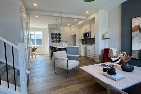 Open concept living space with a kitchen island, seating area, and living room. - 191 Lanark Gate Se, Airdrie