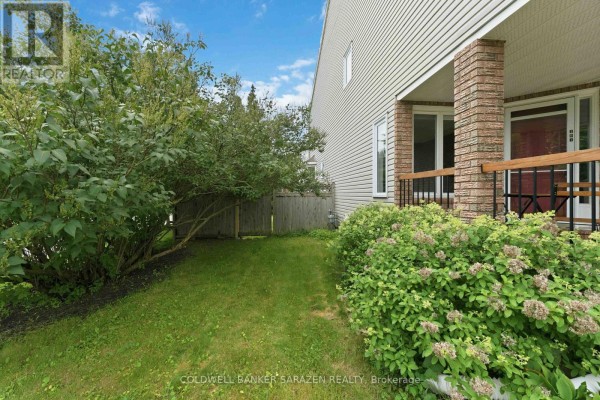 Side view of townhouse with green lawn and shrubs leading to the front entrance. - 191 Markland Crescent, Ottawa