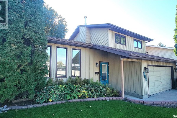 Front view of the house at 191 Neatby Place with mature trees and landscaping. - 191 Neatby Place, Saskatoon