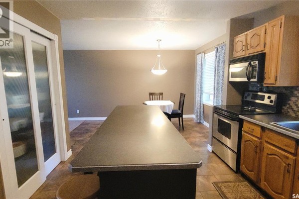 View from the kitchen island towards the dining area with a table and chairs. - 191 Neatby Place, Saskatoon