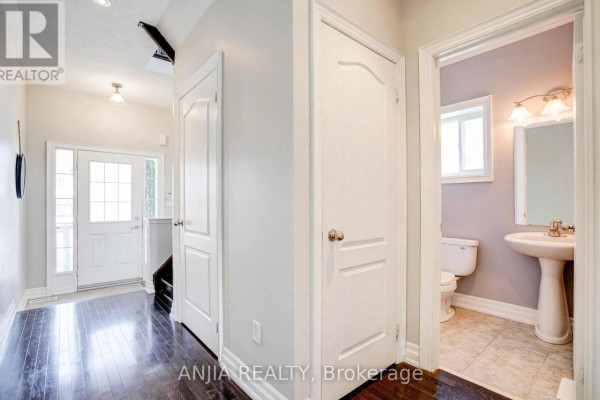 Interior hallway with a view into a powder room featuring a toilet, pedestal sink, and tiled floor. - 191 Reeves Way Boulevard, Whitchurch Stouffville