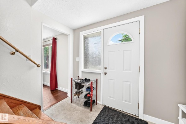 Interior entryway with white door, shoe racks, and view of wooden staircase. - 191 Ridgewood Tc, St  Albert