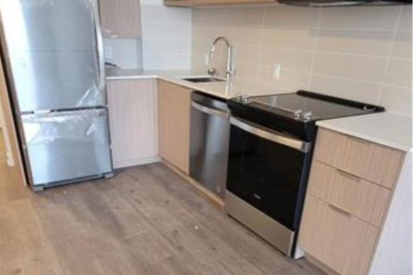 A modern kitchen with light wood cabinets, stainless steel appliances, and a light-colored backsplash. - 1910 - 10 Deerlick Court, Toronto