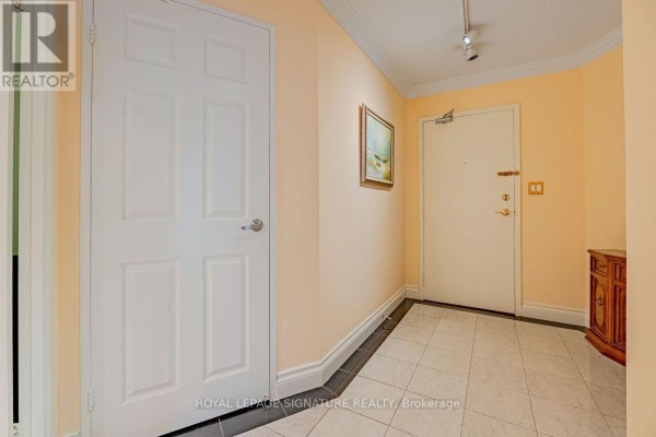 An apartment entrance foyer with peach walls, tiled floor, and two doors. - 1912 - 2000 Islington Avenue, Toronto