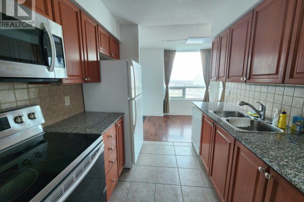 Galley kitchen with wood cabinets, granite countertops, and stainless steel appliances. - 1912 - 83 Borough Drive, Toronto