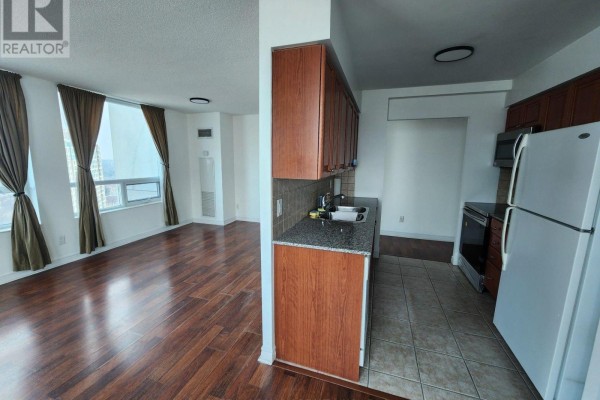 Open-concept living space with a galley kitchen and a living area with large windows. - 1912 - 83 Borough Drive, Toronto