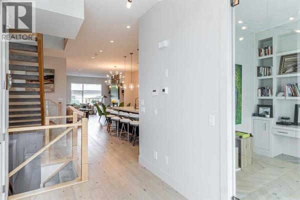 Open concept main floor with hardwood floors, modern staircase, kitchen island, and living area. - 1912 23 Avenue Nw, Calgary