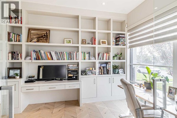 Home office with built-in white shelving, desk, computer, and a large window with blinds. - 1912 23 Avenue Nw, Calgary