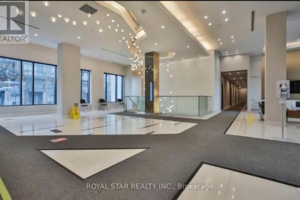 Wide shot of a modern condo lobby with polished floors, abstract lighting, and seating. - 1913 - 35 Watergarden Drive, Mississauga