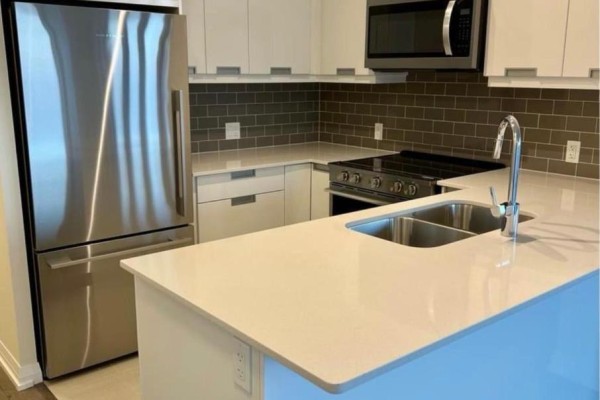 A bright, modern kitchen with white cabinetry, stainless steel appliances, and a quartz island. - 1913 - 35 Watergarden Drive, Mississauga